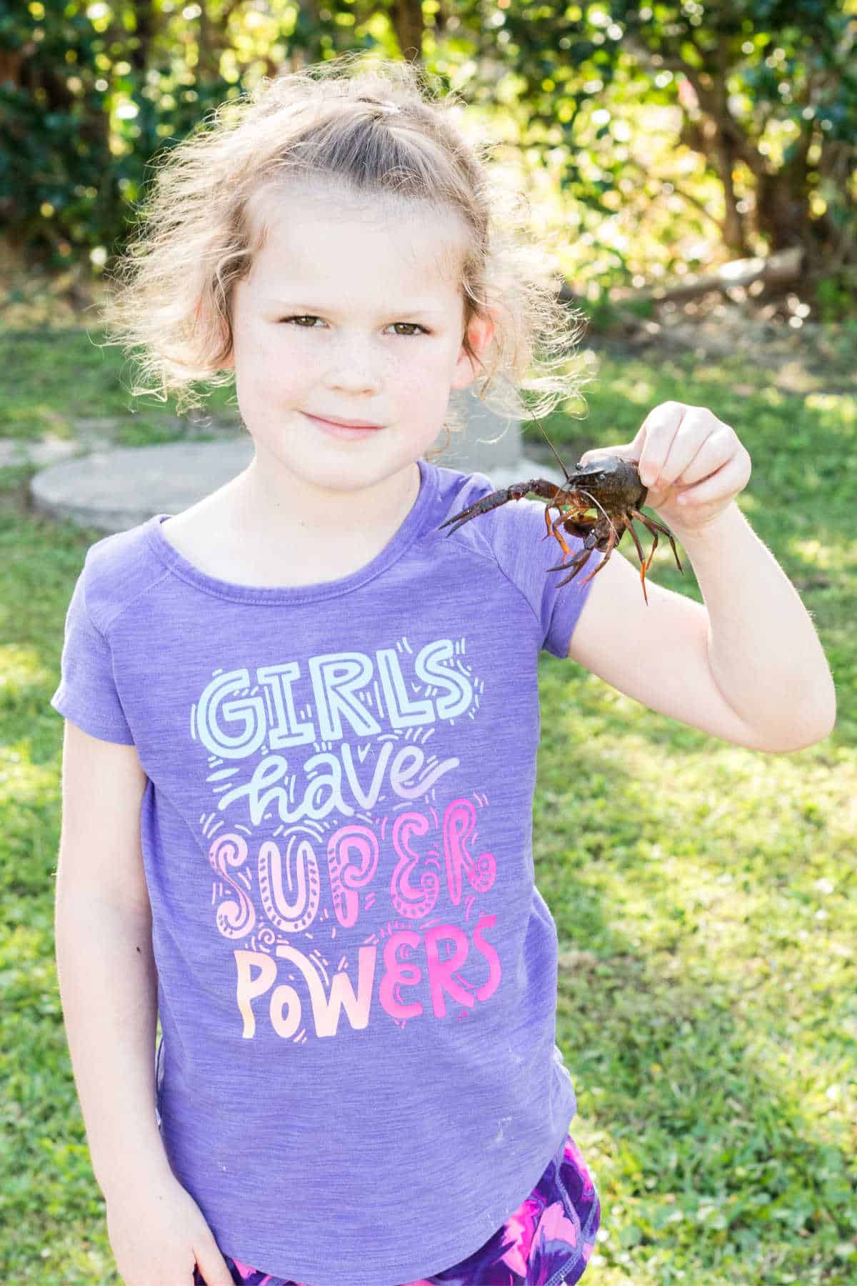 a child holding up a crawfish