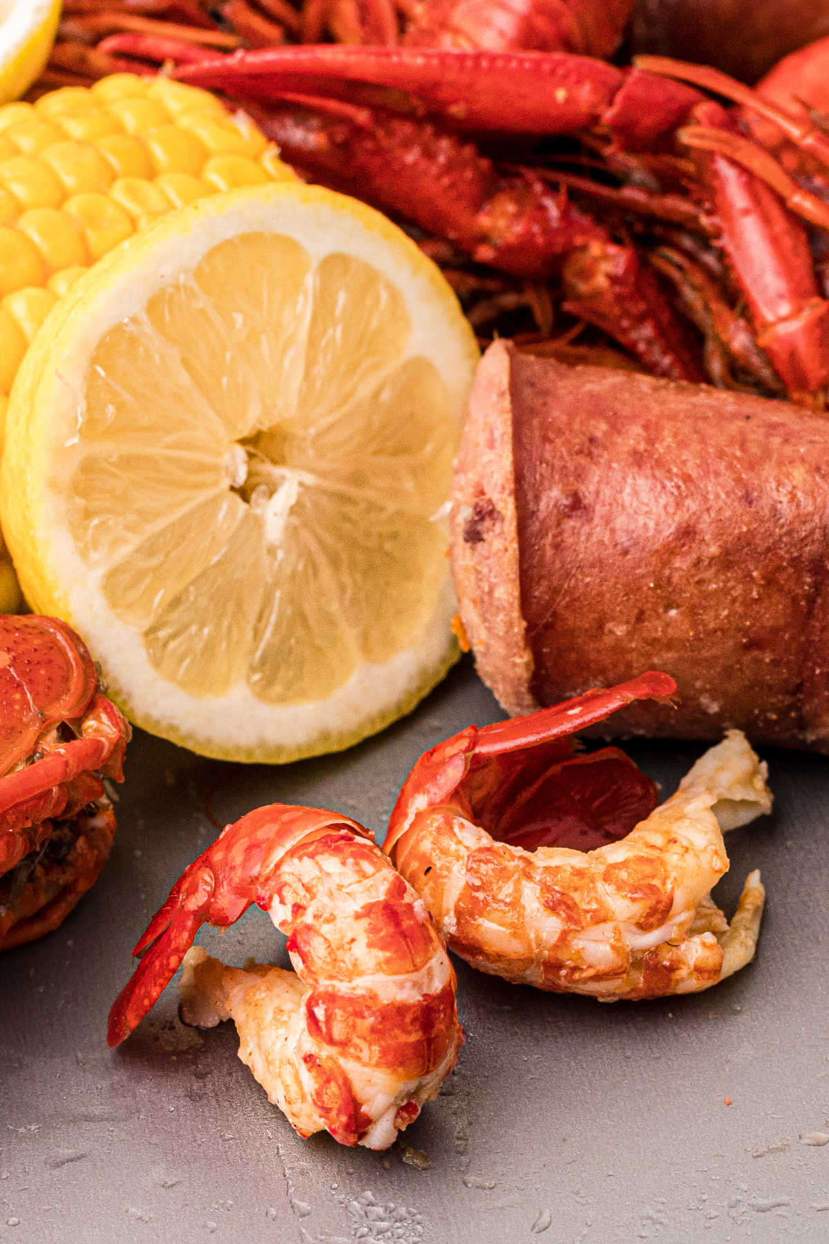 close up of peeled crawfish with sausage and corn in the background