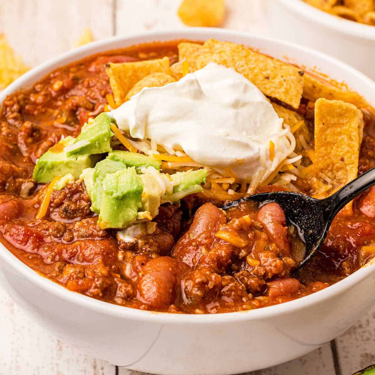 close up of a bowl of venison chili with beans and sour cream on top