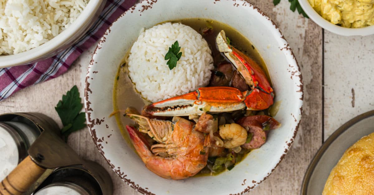 close up of a bowl of seafood gumbo with a crab and shrimp with a spoon of rice