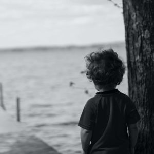 boy leaning against tree signs of autism