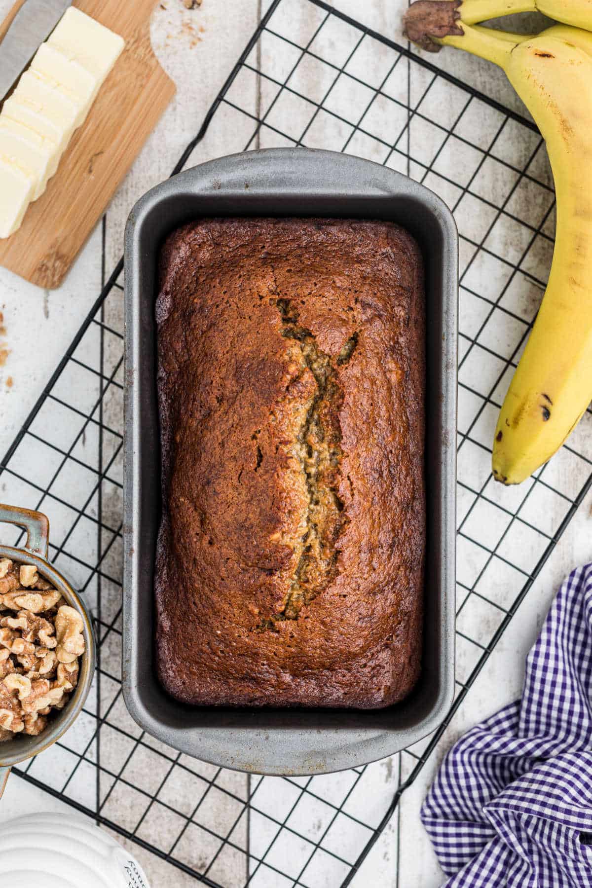 a loaf tin with banana bread on a cooling rack