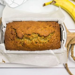banana bread in pan with bananas on side