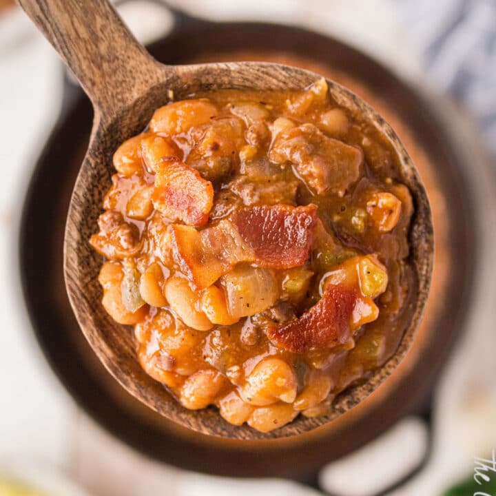 a close up of a spoon full of baked beans with bacon