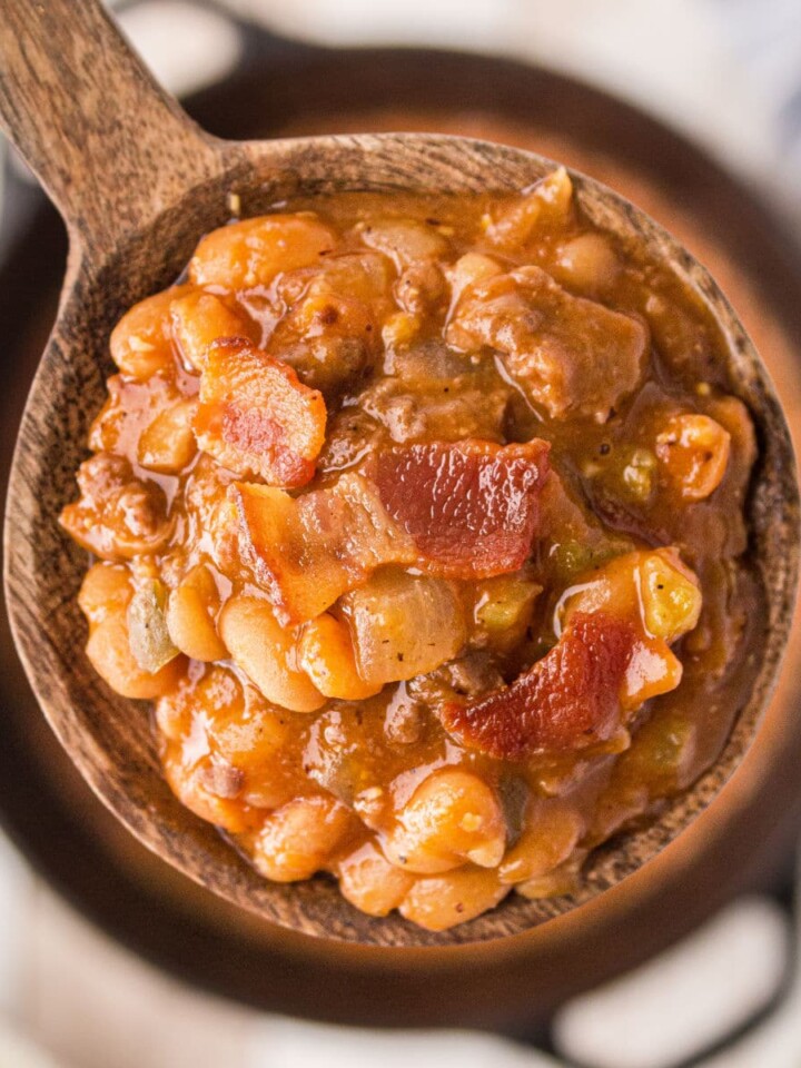 a close up of a spoon full of baked beans with bacon