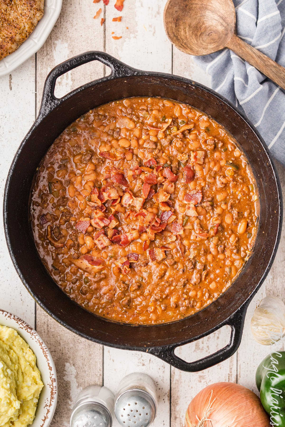 a big cast iron pot full of southern baked beans with some bacon on top