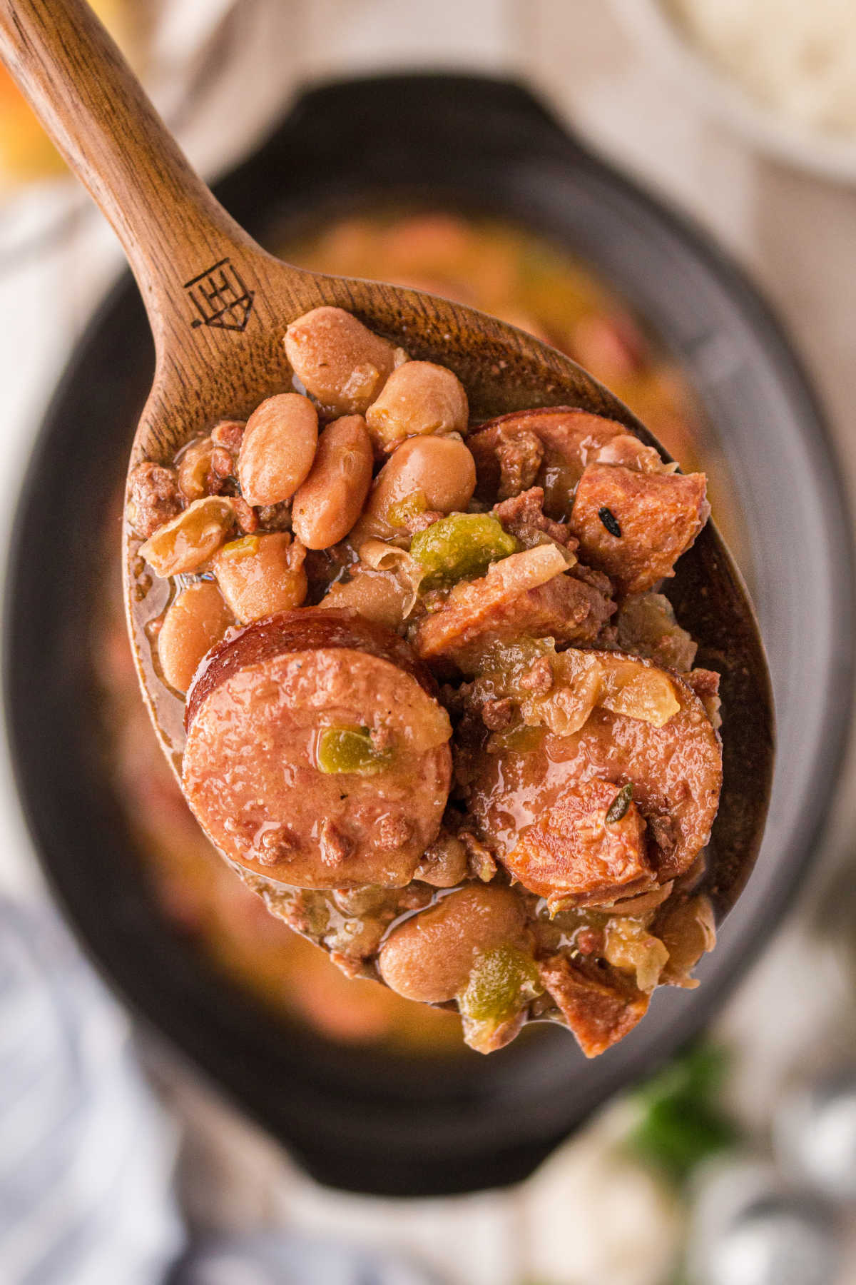 close up of some pinto beans and sausage on a spoon over a crock pot