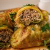 cabbage rolls in pile with one sliced open showing the stuffed meat inside