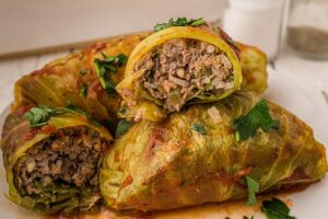 cabbage rolls in pile with one sliced open showing the stuffed meat inside