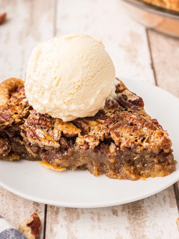 a plate with a slice of pecan pie with a ball of ice cream sitting on top