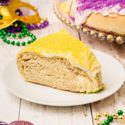 slice of mardi gras king cake on a plate with yellow sugar on top