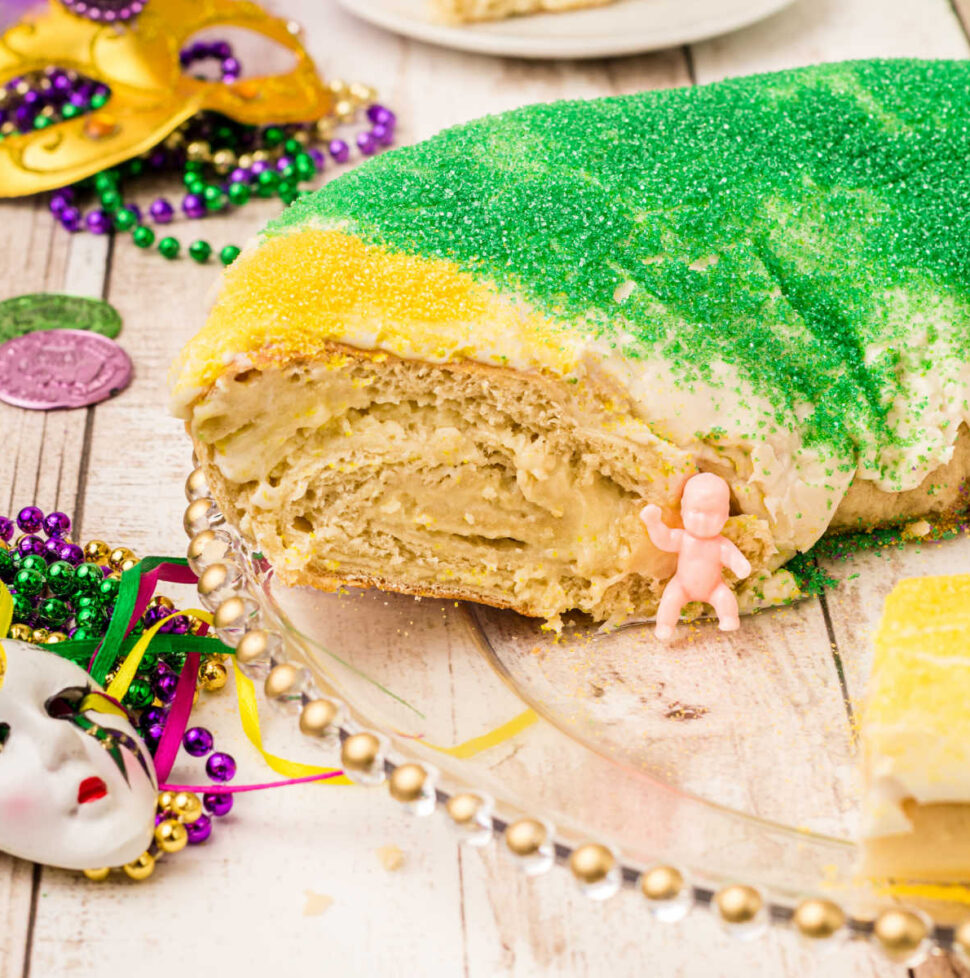 a king cake with a piece cut out with the king cake baby sitting there