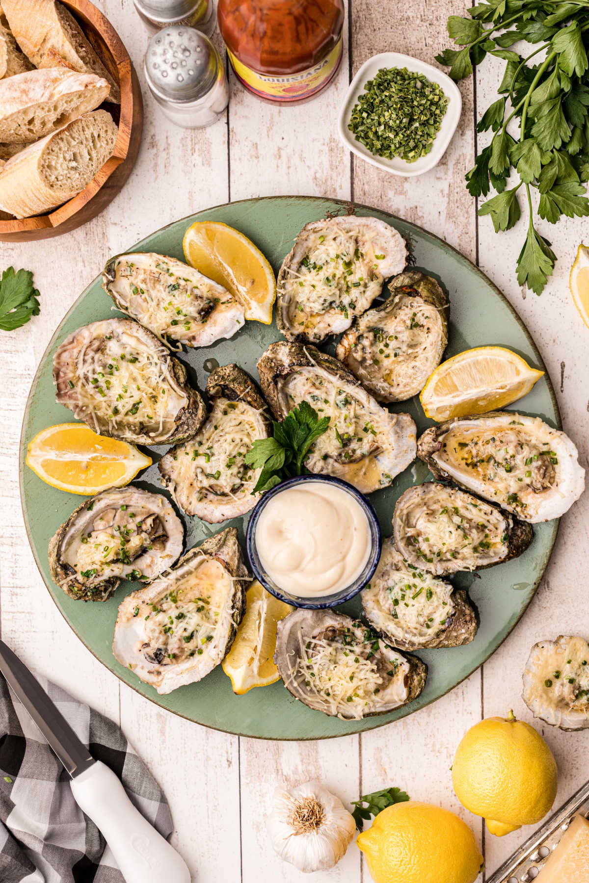 a round plate full of chargrilled oysters with lemon wedges