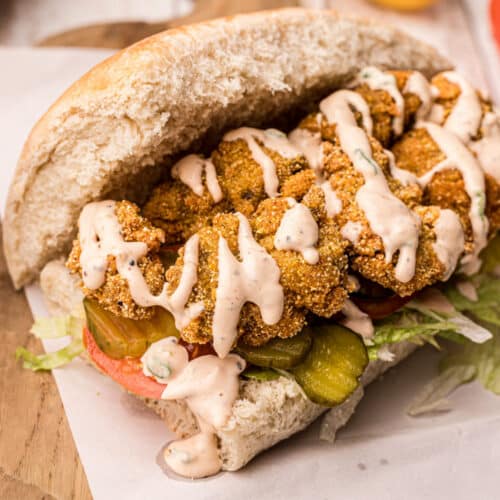 Po Boy bread filled with crispy fried oysters and remoulade sauce drizzled over the top