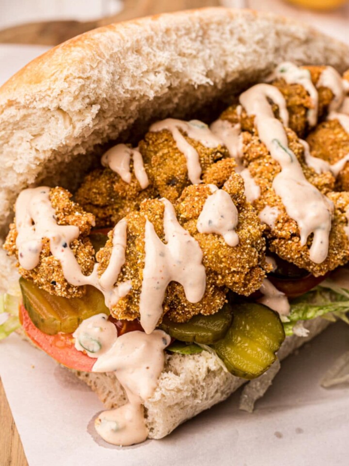 Po Boy bread filled with crispy fried oysters and remoulade sauce drizzled over the top