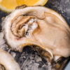 raw oyster on ice with lemon wedge