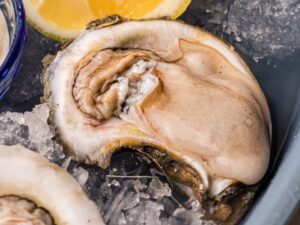 raw oyster on ice with lemon wedge
