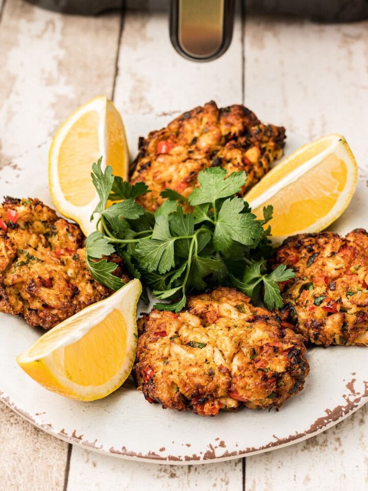 A plate of air fryer crab cakes with lemon wedges.