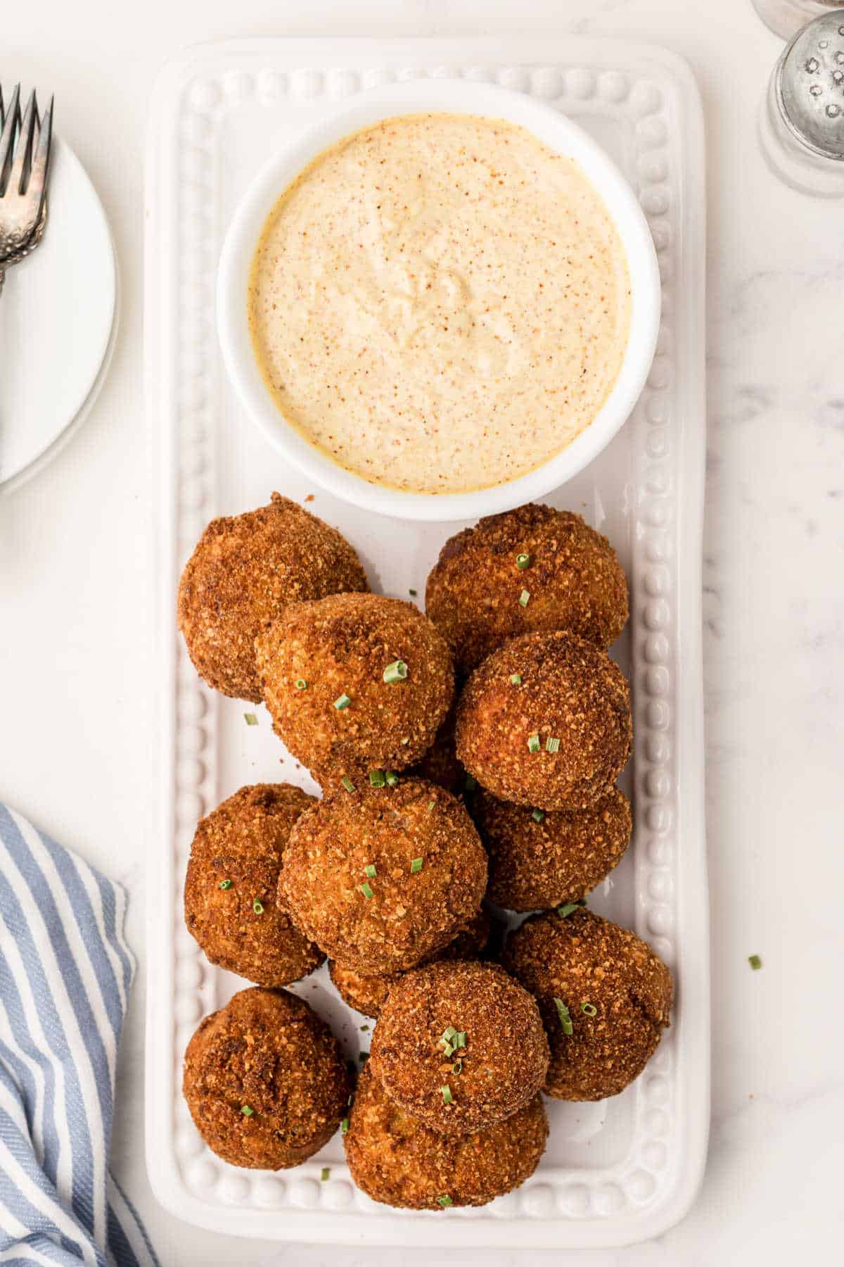 Fried boudin balls on a platter with mustard cream sauce