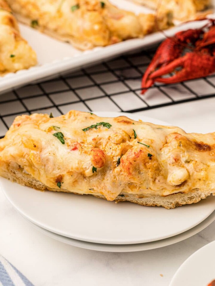 a slice of crawfish bread on a plate with a cooked crawfish behind