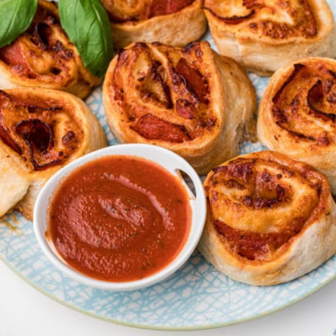 homemade air fryer pizza rolls on a plate with a dipping sauce