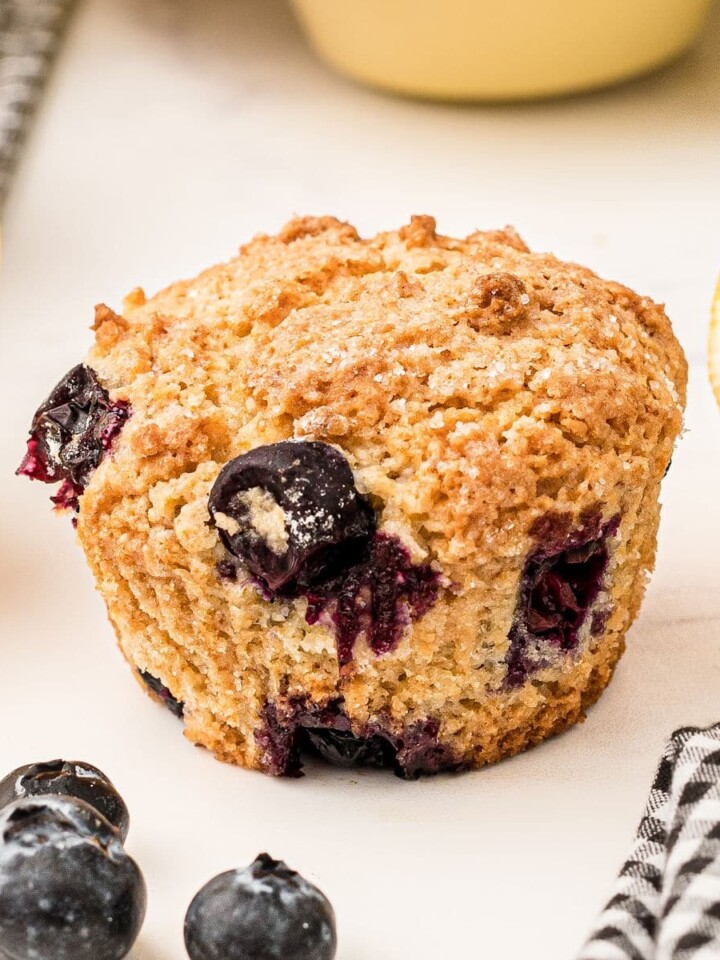 Close up of a lemon blueberry muffin with some lemons on the side.
