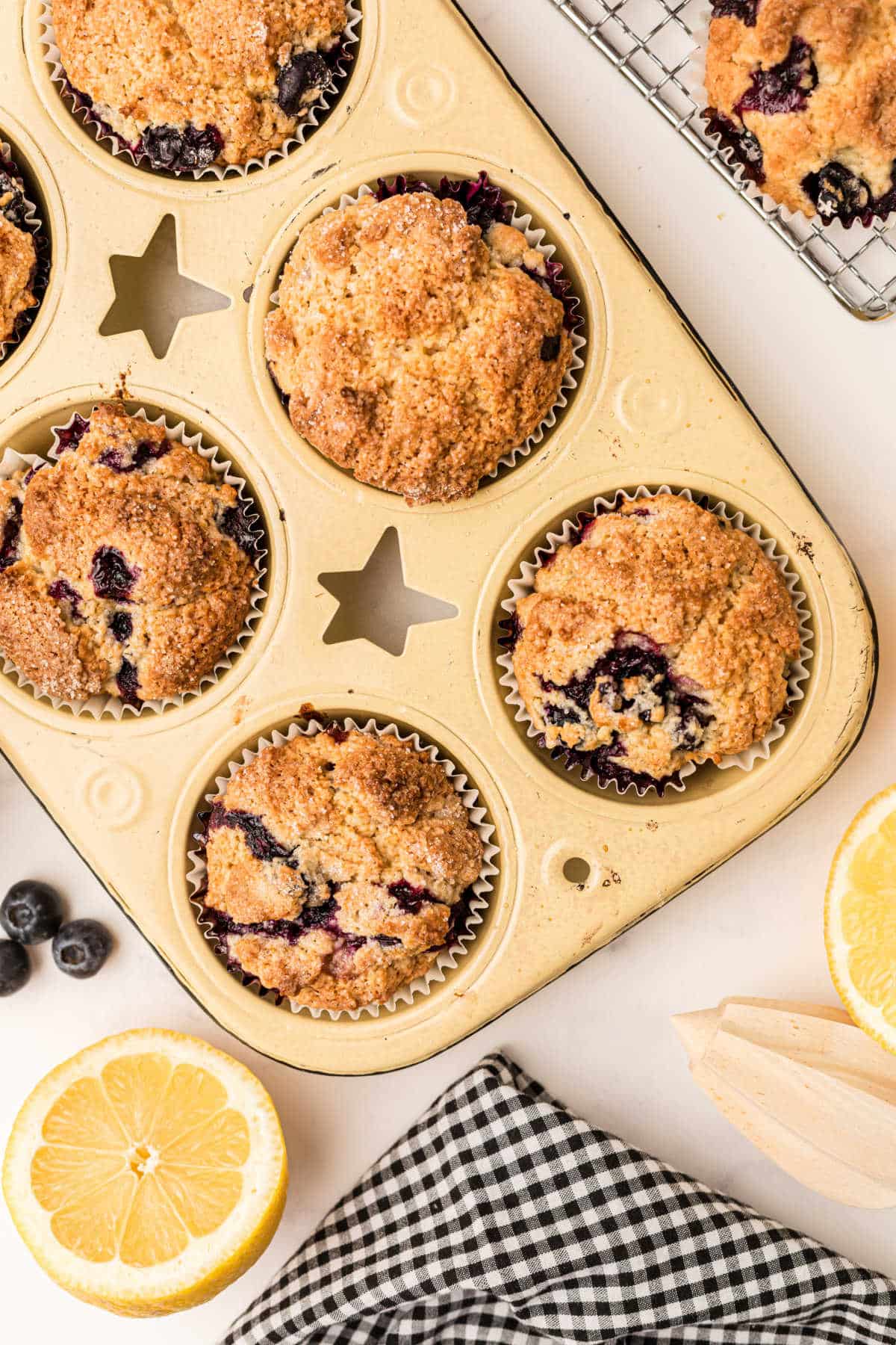 a muffin tin with lemon blueberry muffins cooked