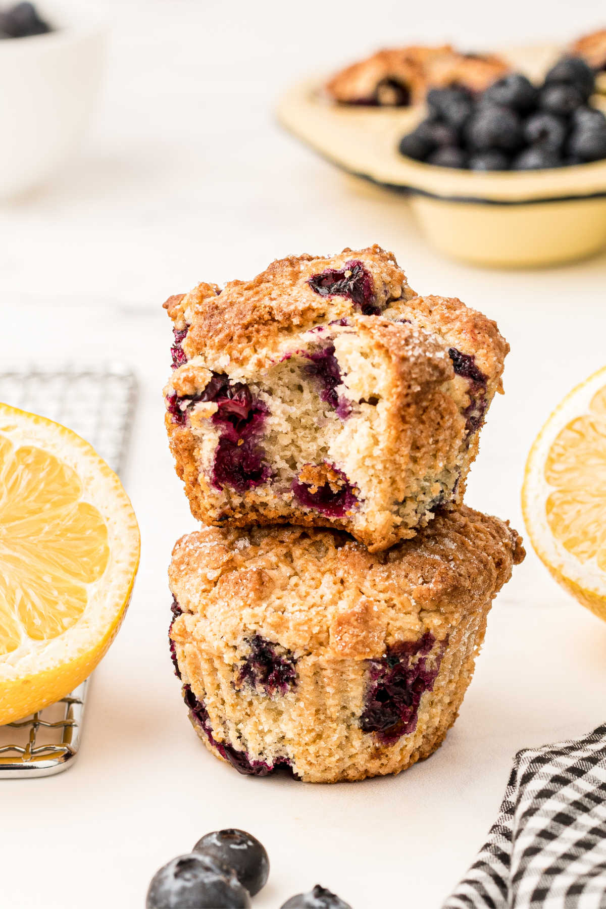 two lemon and blueberry muffins with sour cream stacked with the top one with a bite taken out