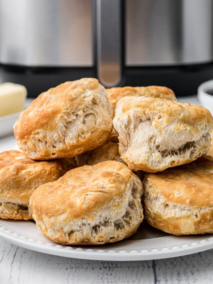 a plate of biscuits piled high, in front of an air fryer