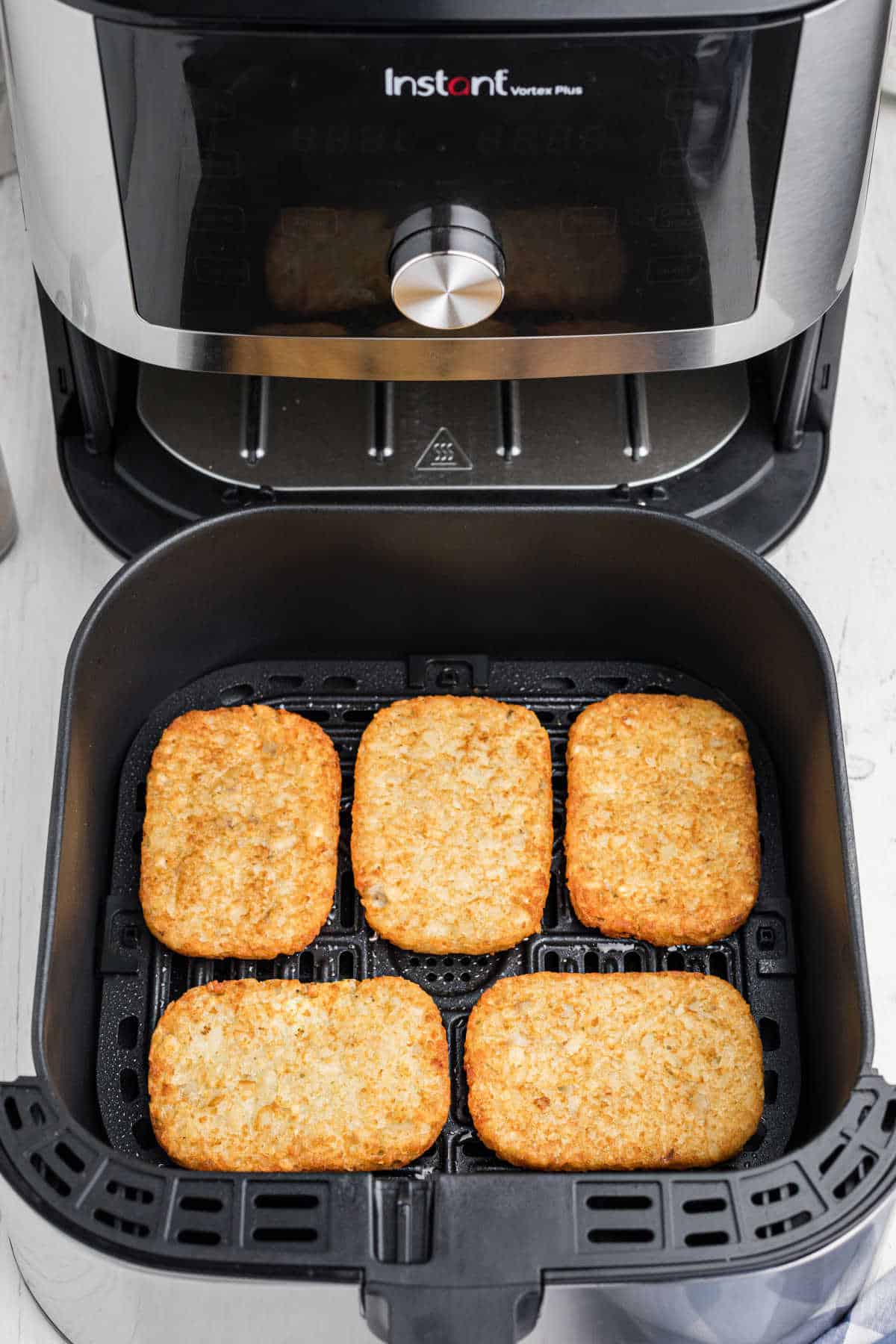 an open air fryer showing 5 hash browns cooked