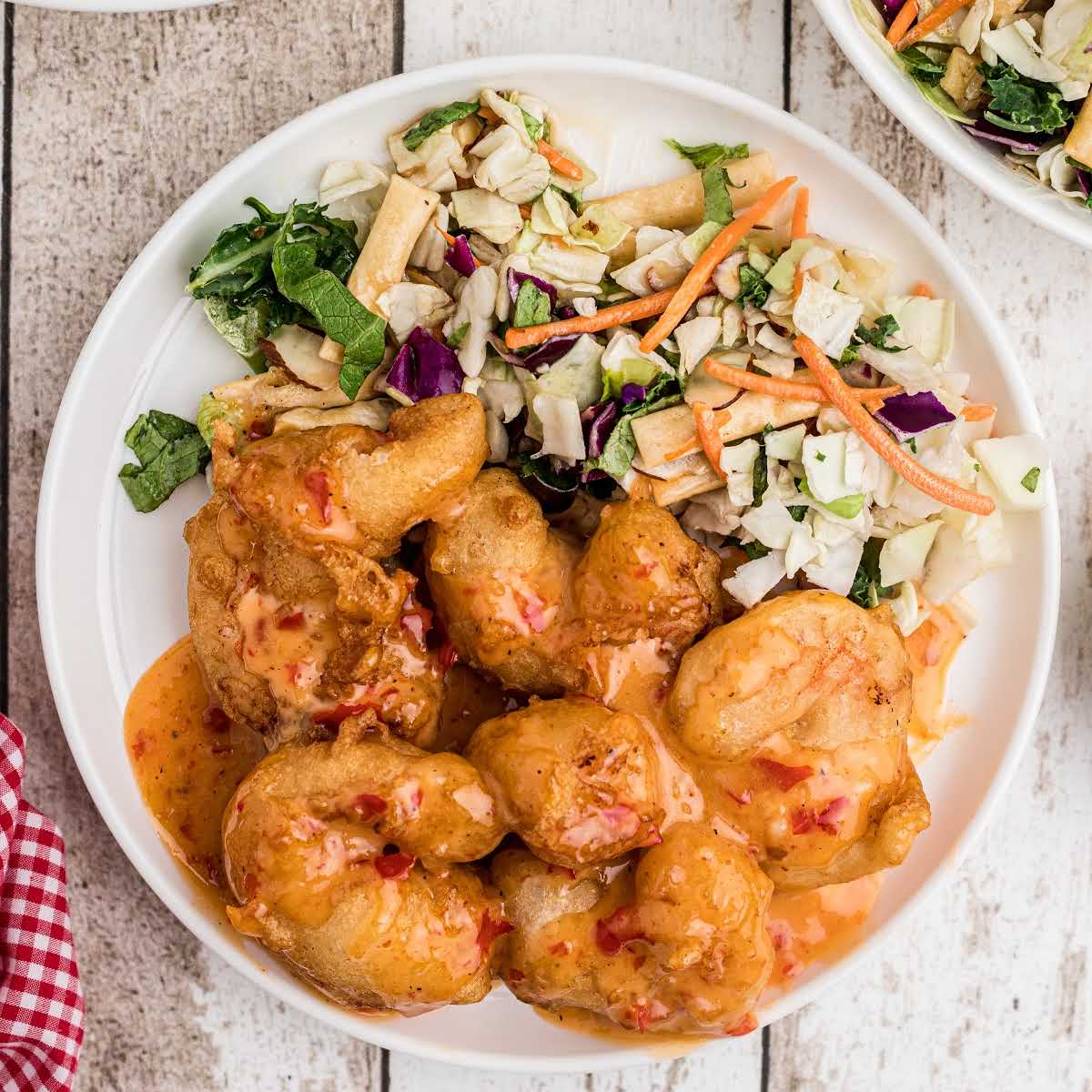 overhead image of battered shrimp that has been fried and coated in sauce with a side salad