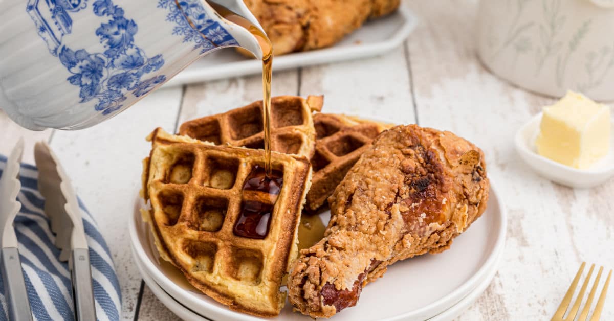 southern fried chicken with a side of waffles with syrup being poured over the waffles