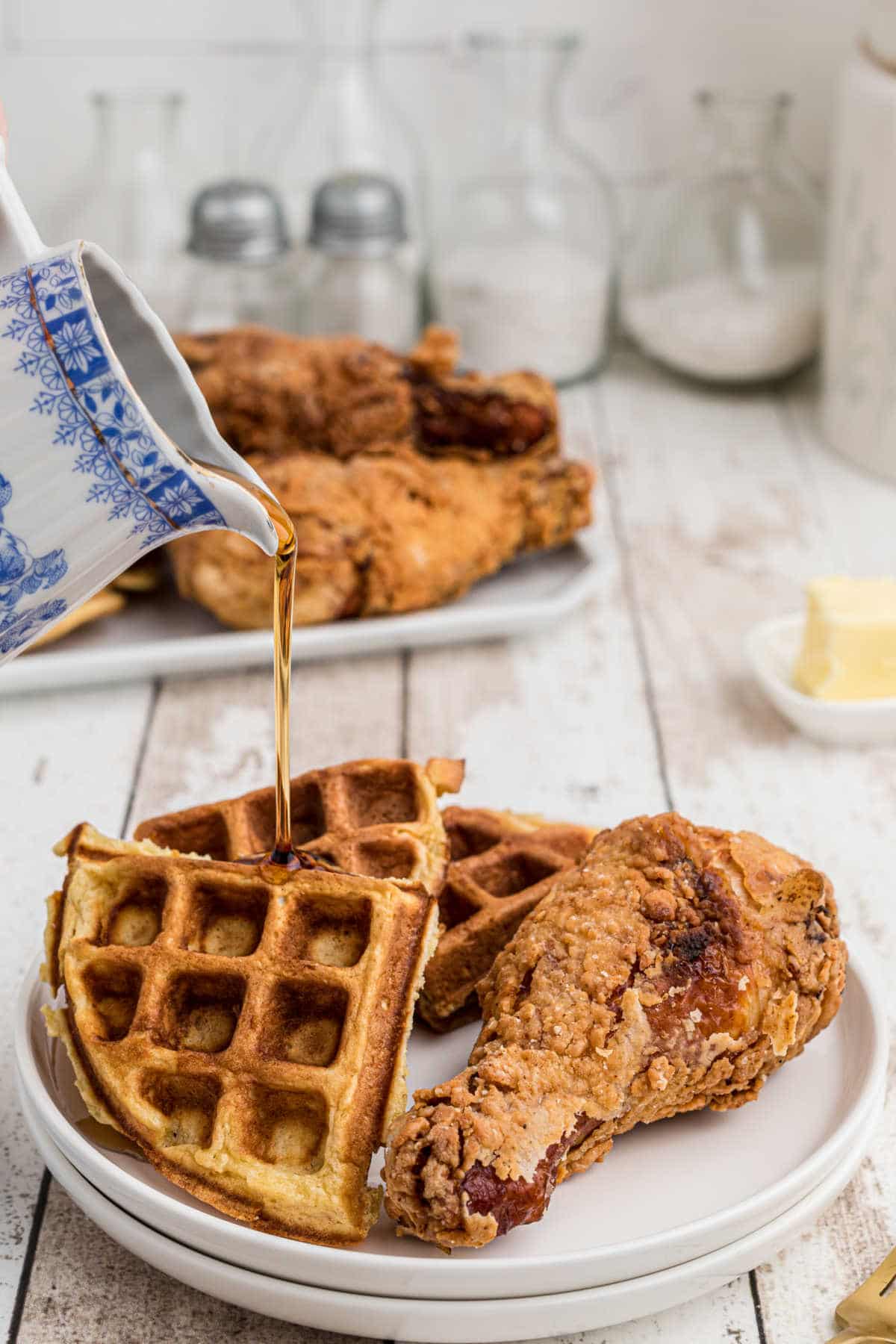 a plate with fried chicken and waffles on it with syrup being poured over the top