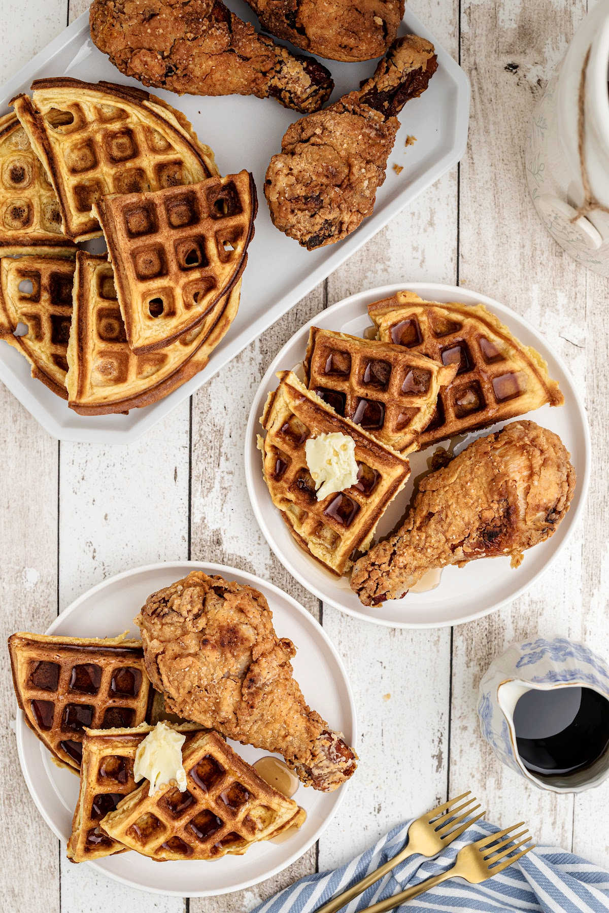 A dish of fried chicken and waffles with syrup on them on dished out plates