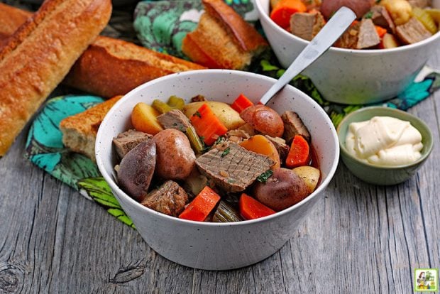 slow cooker venison stew with potatoes and carrots. Bread in the background with mayonnaise