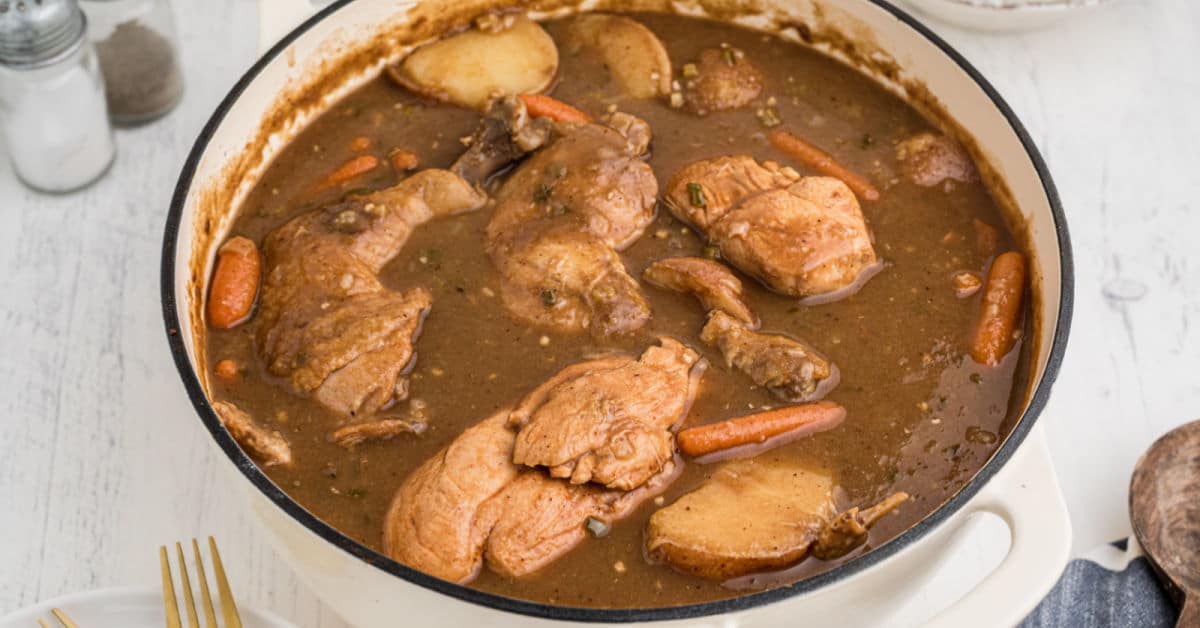 a pot full of chicken and brown gravy with carrots and potatoes