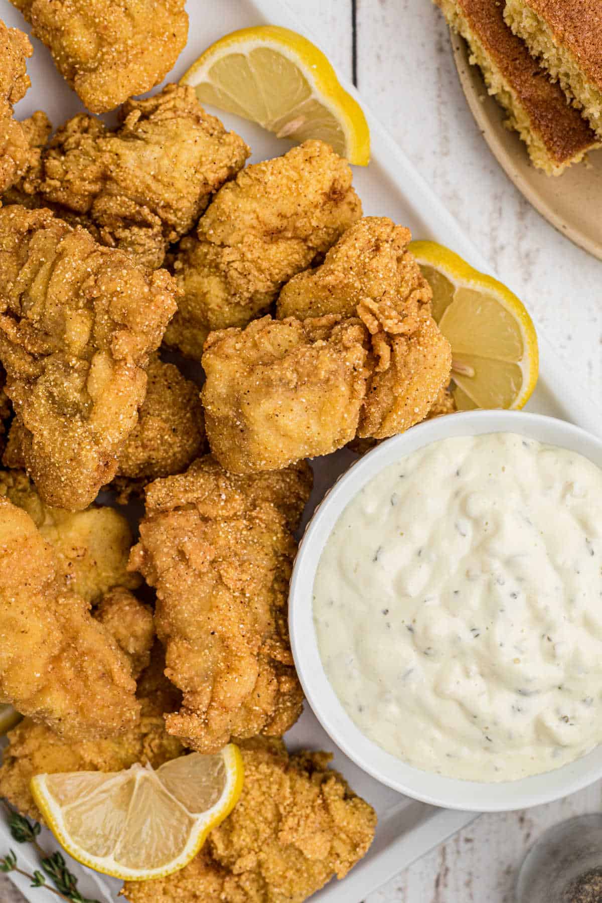 A plate of fried catfish nuggets with some slices of lemon and tartar sauce