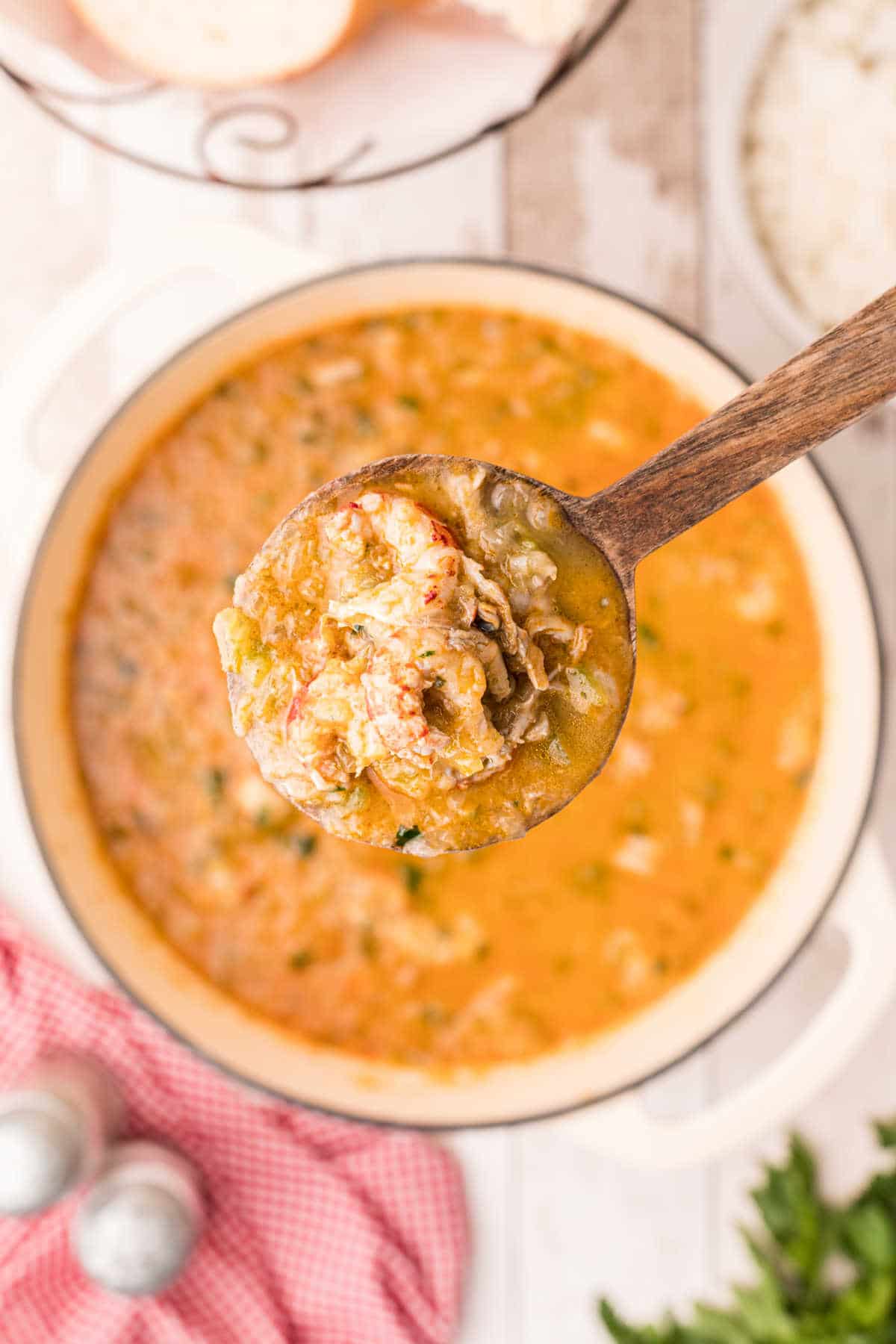 A spoon full of crawfish etouffee over a pot in the background