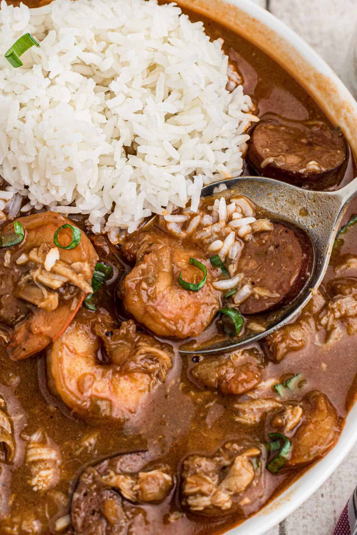 Louisiana seafood gumbo recipe close up of a bowl with some rice and a spoon digging in.