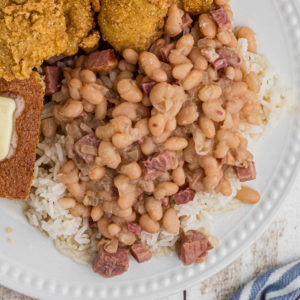 close up of white beans over rice on a plate with catfish peeking in