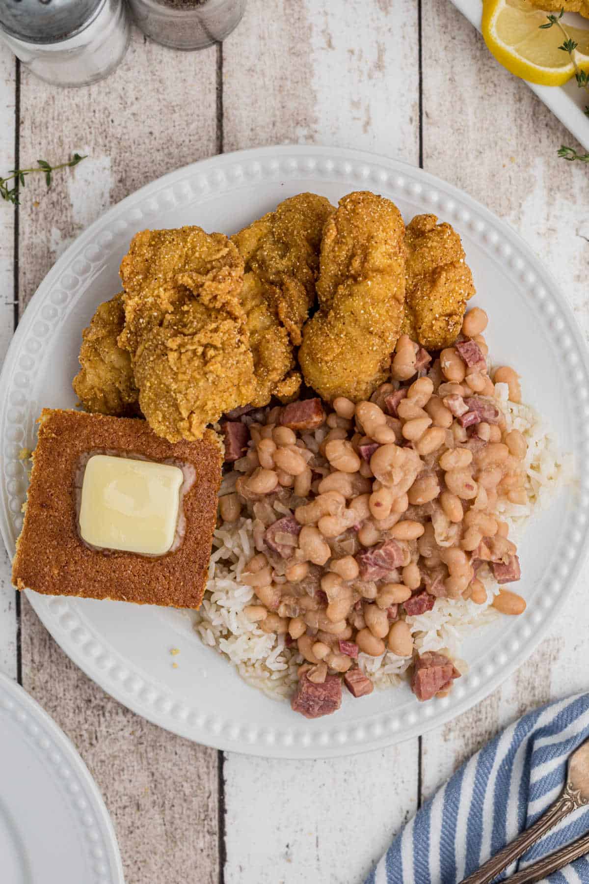 overhead shot of a plate of white beans and rice with fried catfish and cornbread