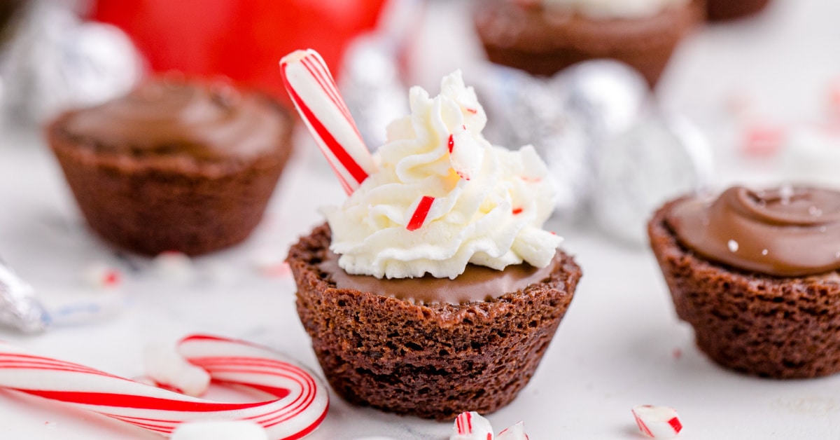 close up of a hot chocolate brownie, with whipped cream on the top scattered with peppermint sticks