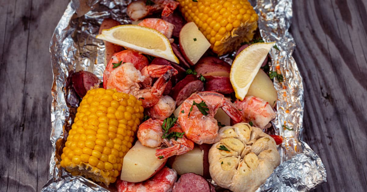 a foil packet full of shrimp, potatoes, garlic, corn and sausage