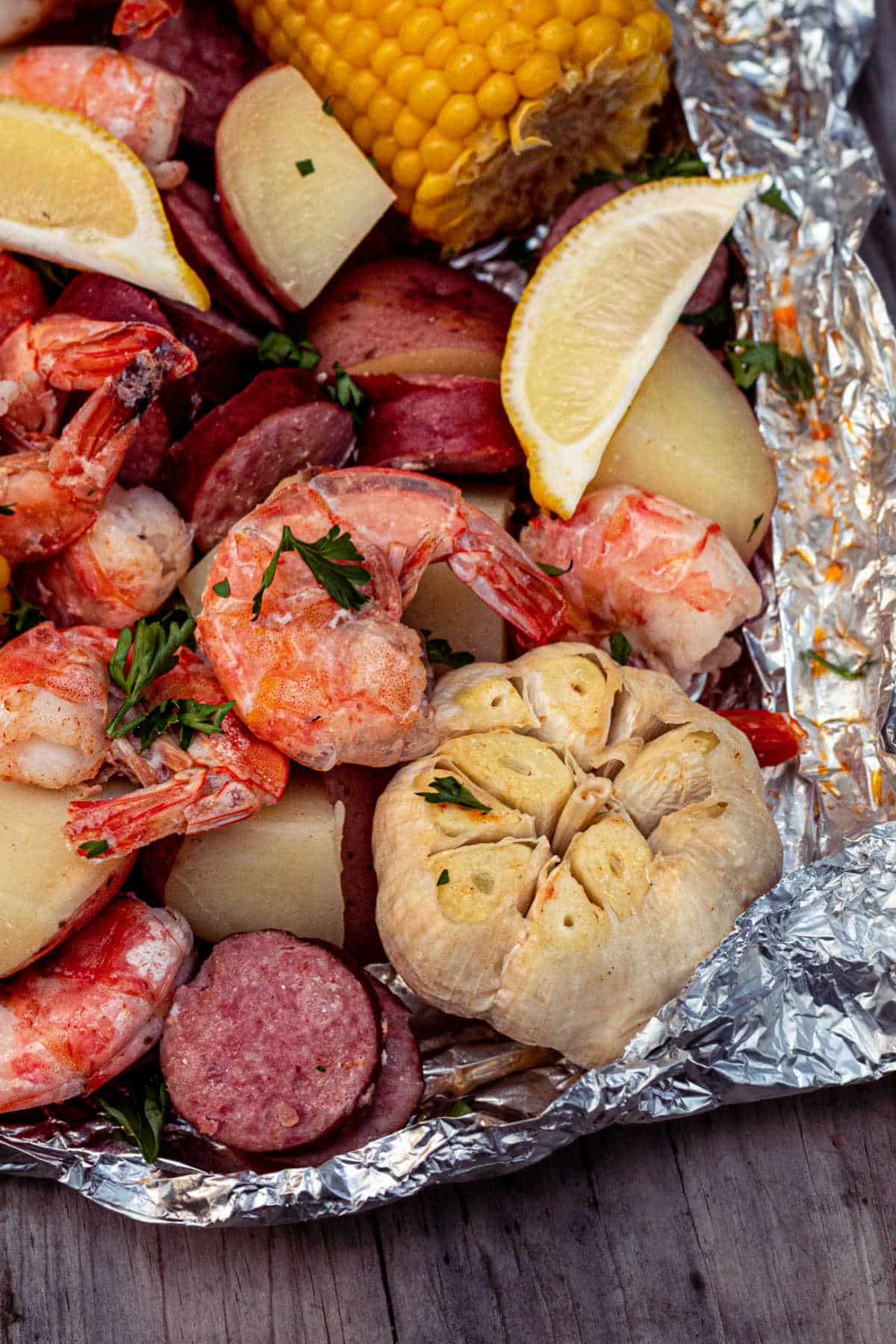 a foil packet full of shrimp, potatoes, garlic, corn and sausage