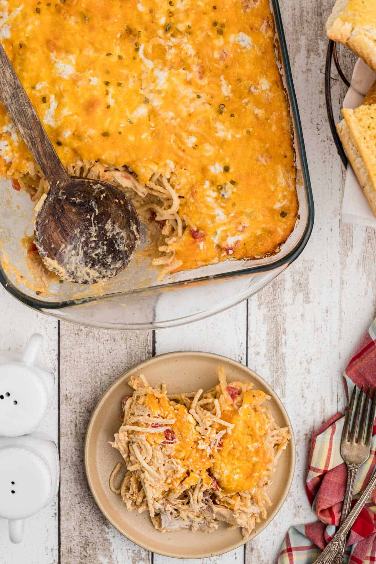 a casserole dish with cheesy chicken spaghetti with a scoop out on a plate
