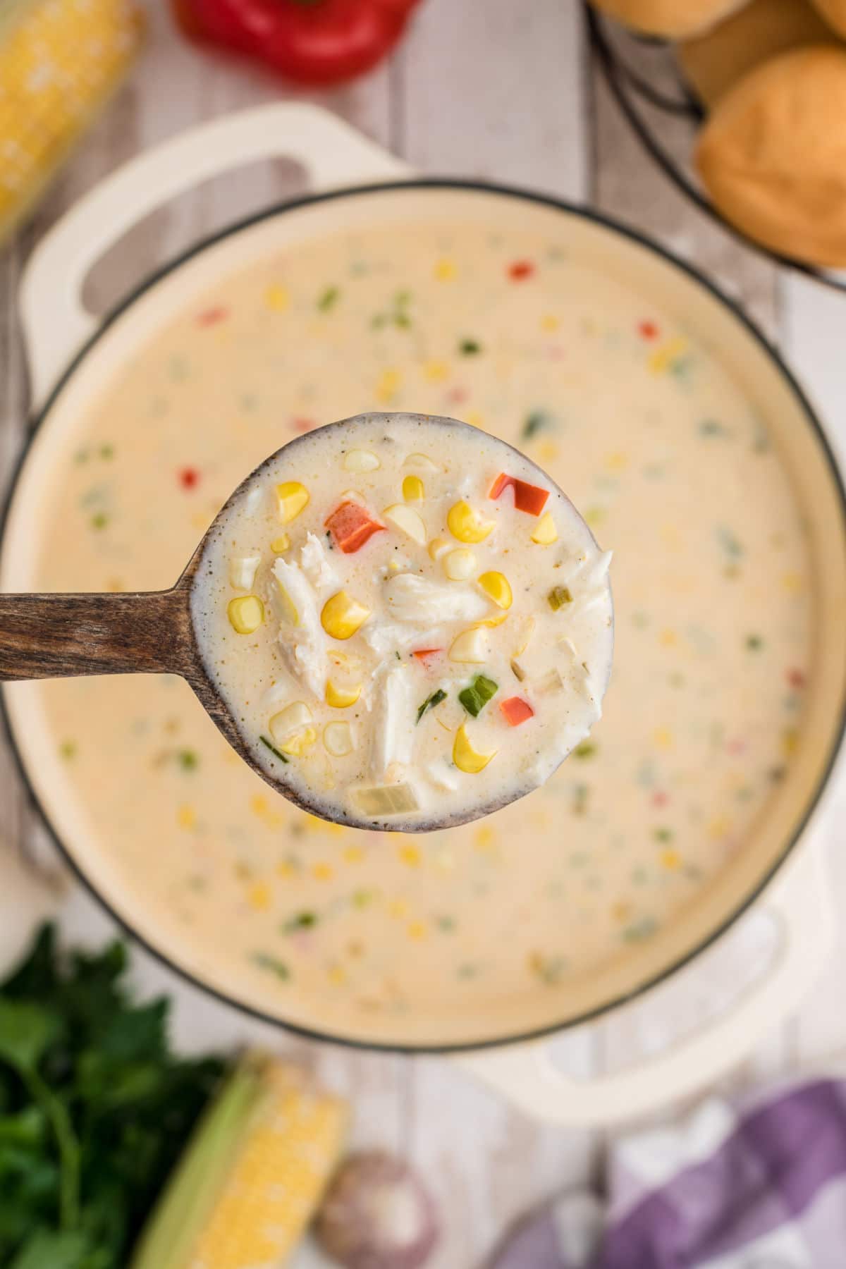 close up of a spoon full of corn and crab bisque above the pot