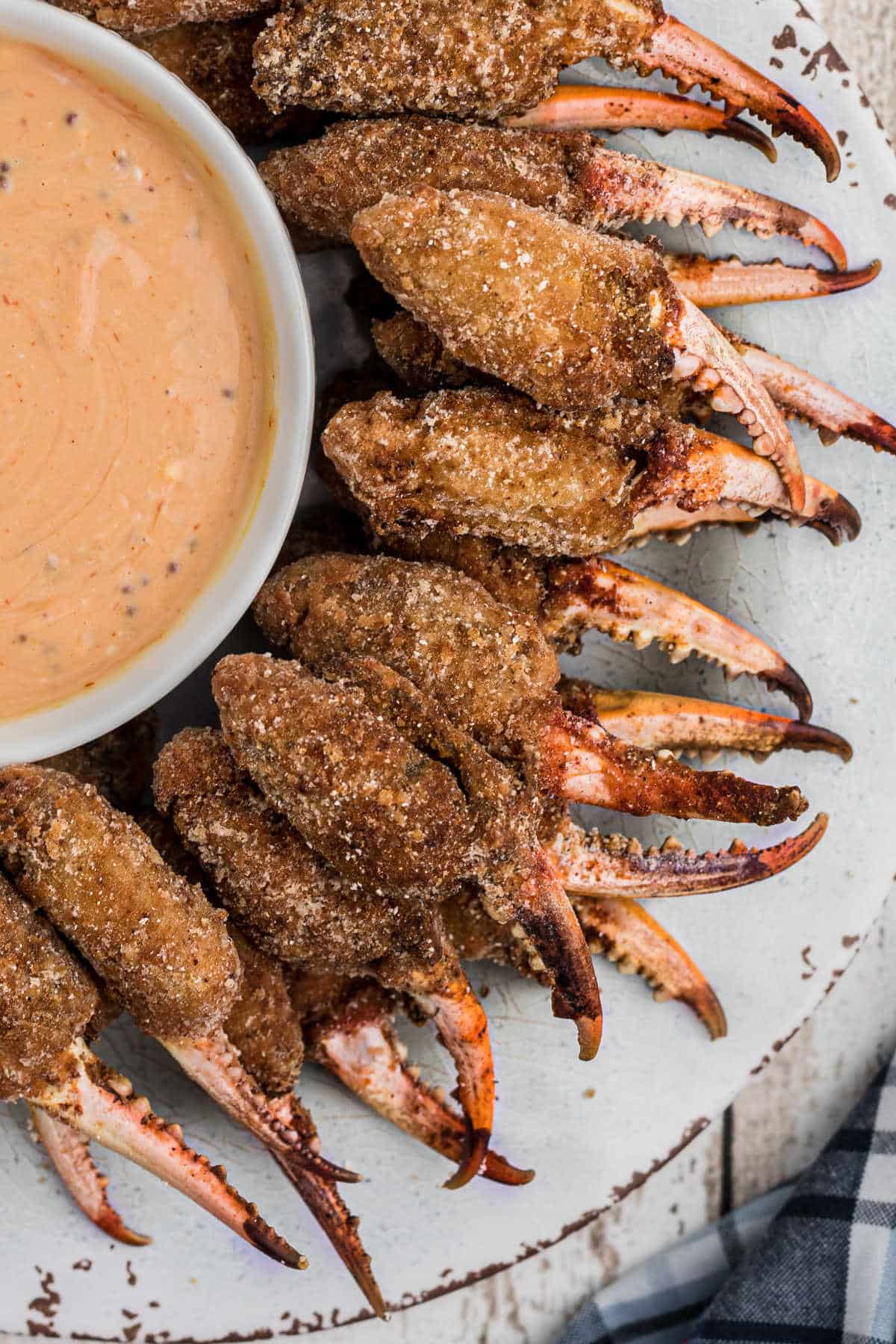 a plate full of fried crab claws around a bowl of dip