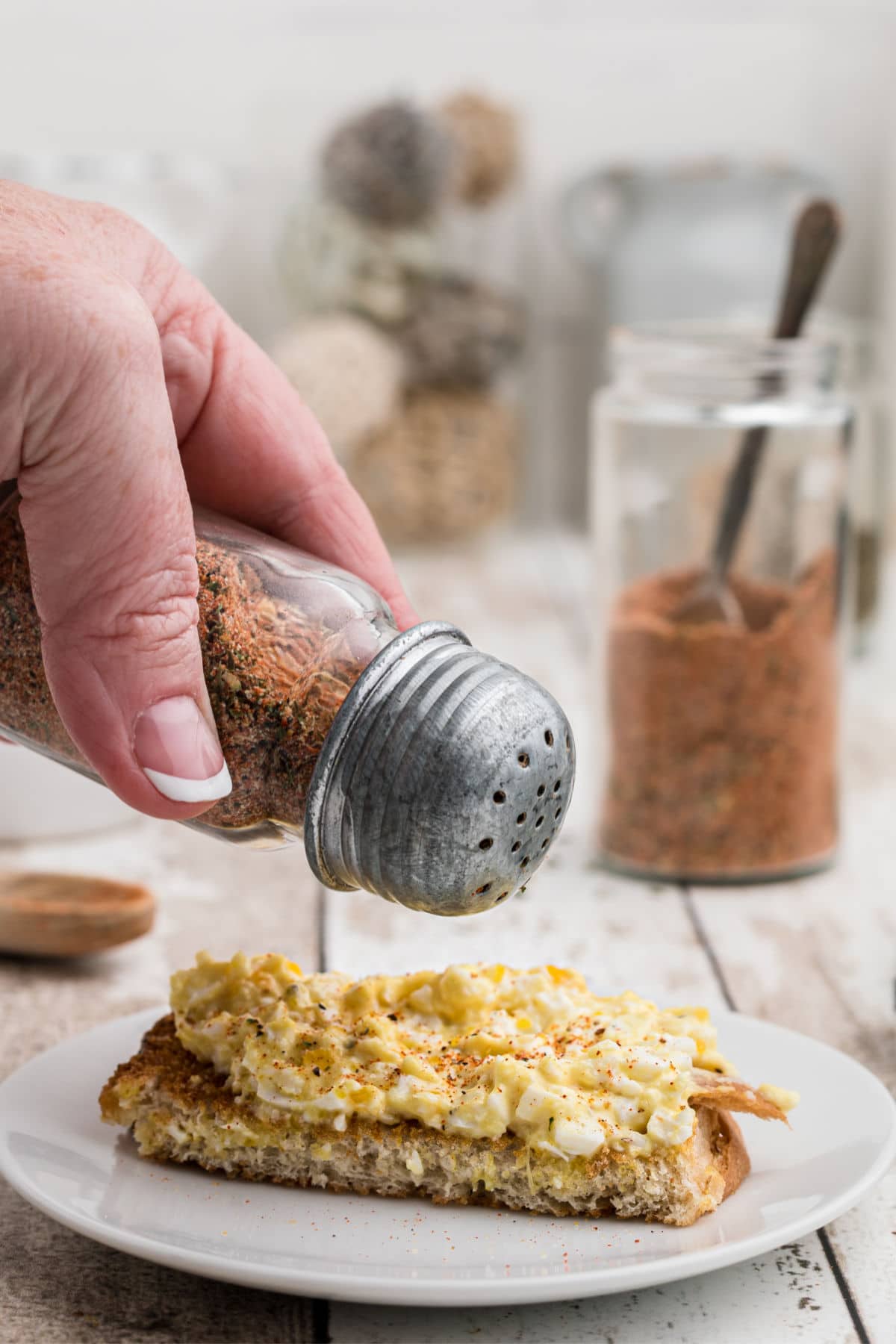 using a salt shake to season some eggs on toast