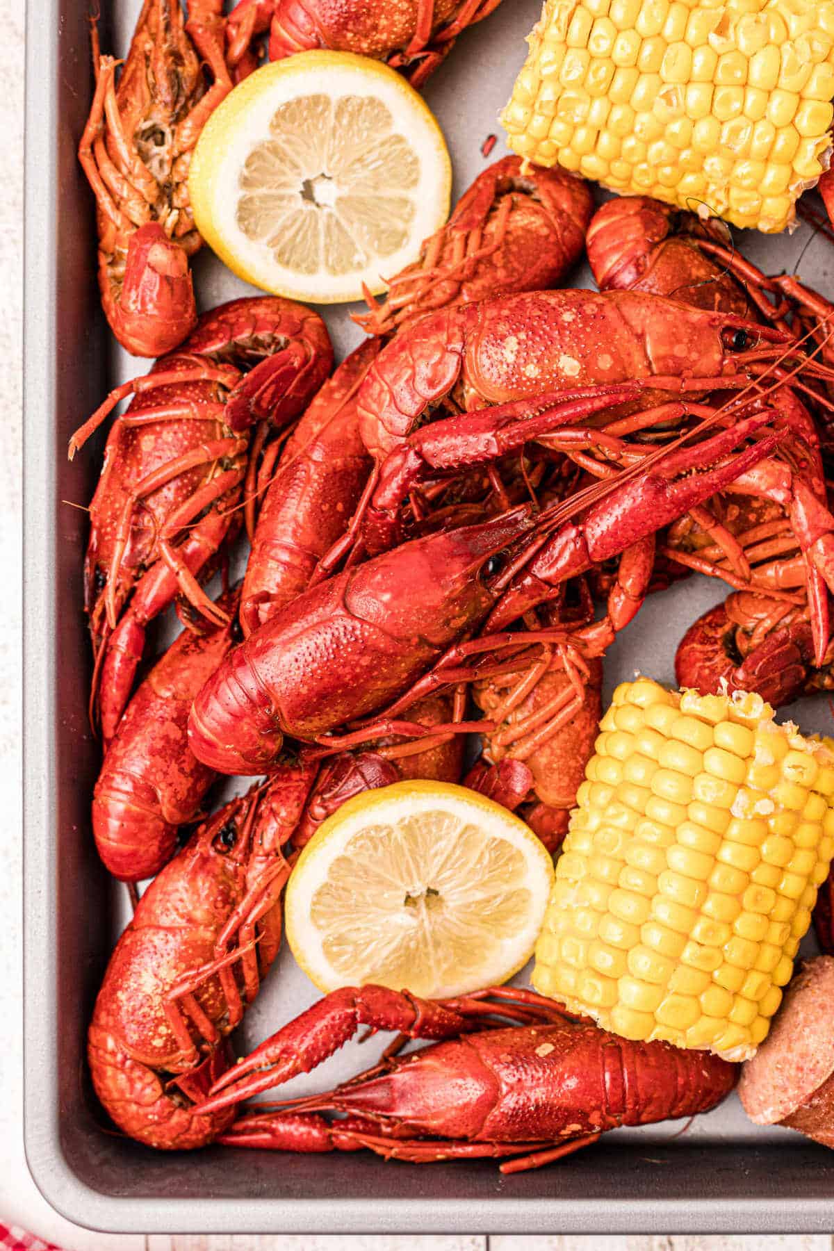 close up of some boiled crawfish on a platter with corn and lemons and sausage