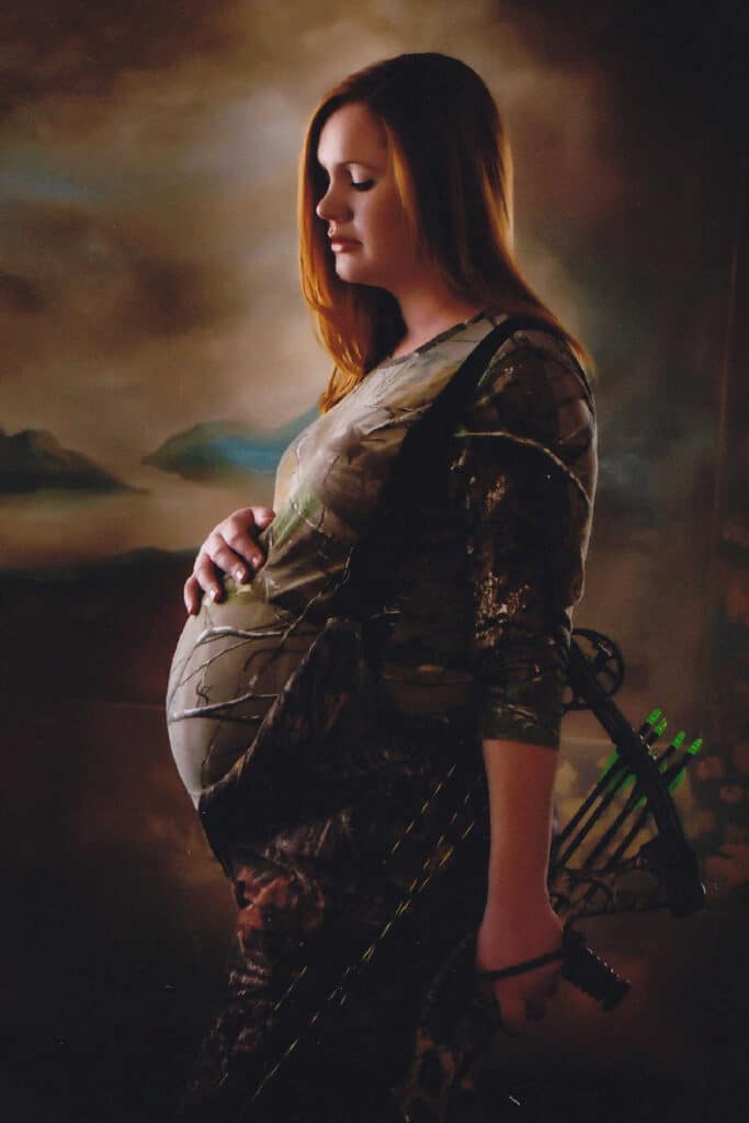 Side shot of Melanie Cagle, pregnant, carrying a bow and arrow.
